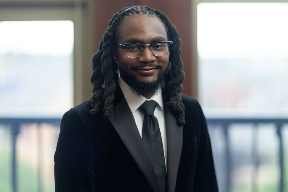 Image 1 of 2 Man in suit smiling for a photo, blurred background